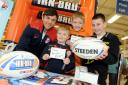 Jon Wilkin signs autographs with, from left, George Lawrenson, seven, Jordan Hodkinson, 10, and Brandon Twiss, 10, when the Saints star popped into the new Tesco Extra store next to Langtree Park.