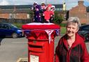 Patricia Meakin next to her Jubilee post box topper in Prescot
