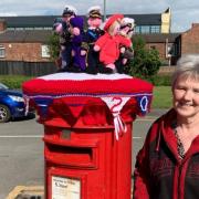 Patricia Meakin next to her Jubilee post box topper in Prescot
