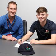 Matthew Hurst, right, signs his first professional contract with Lancashire as Performance Director Mark Chilton looks on