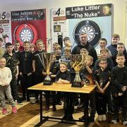 Luke Littler with his trophies and young platers at St Helens Darts Academy