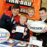 Jon Wilkin signs autographs with, from left, George Lawrenson, seven, Jordan Hodkinson, 10, and Brandon Twiss, 10, when the Saints star popped into the new Tesco Extra store next to Langtree Park.